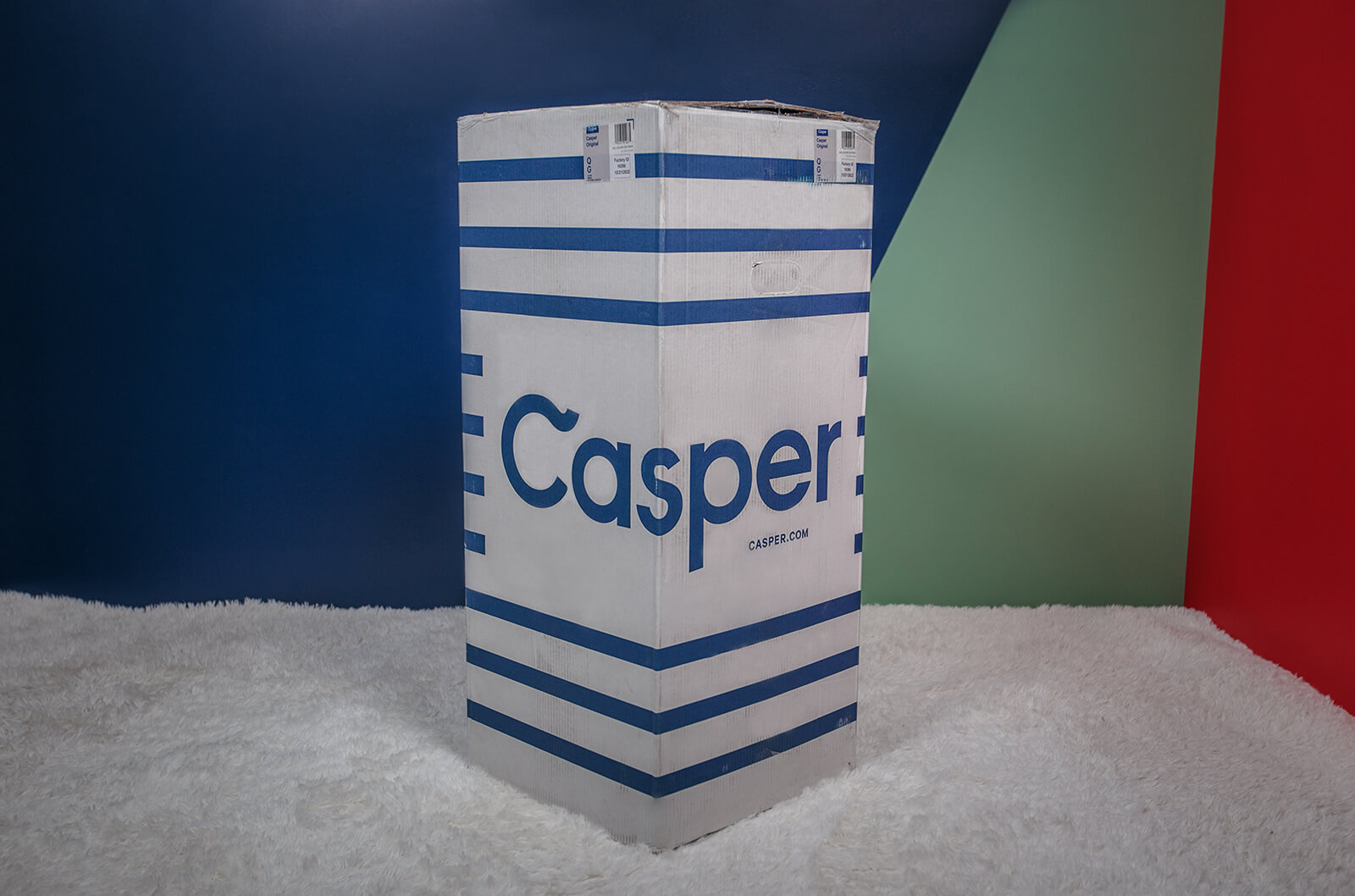 Photo of the Casper Original Mattress box on the floor in a bedroom taken from a front angle.
