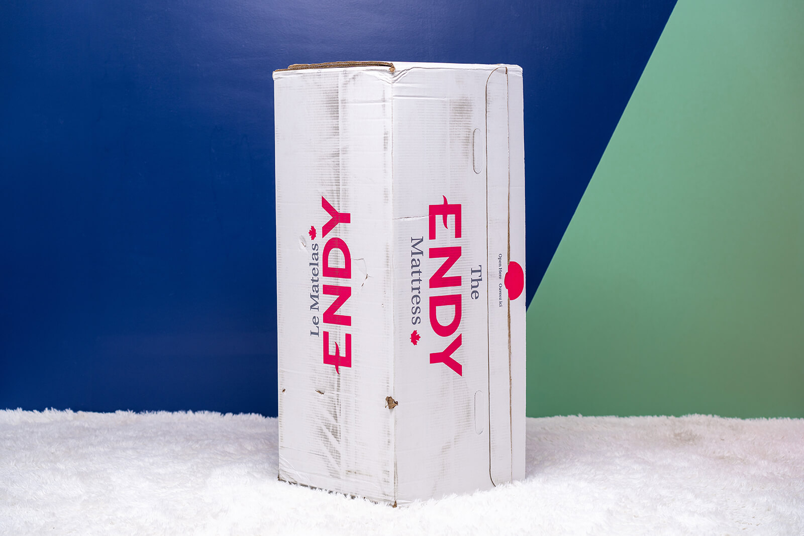 Photo of the Endy Mattress box on the floor in a bedroom taken from a front angle.