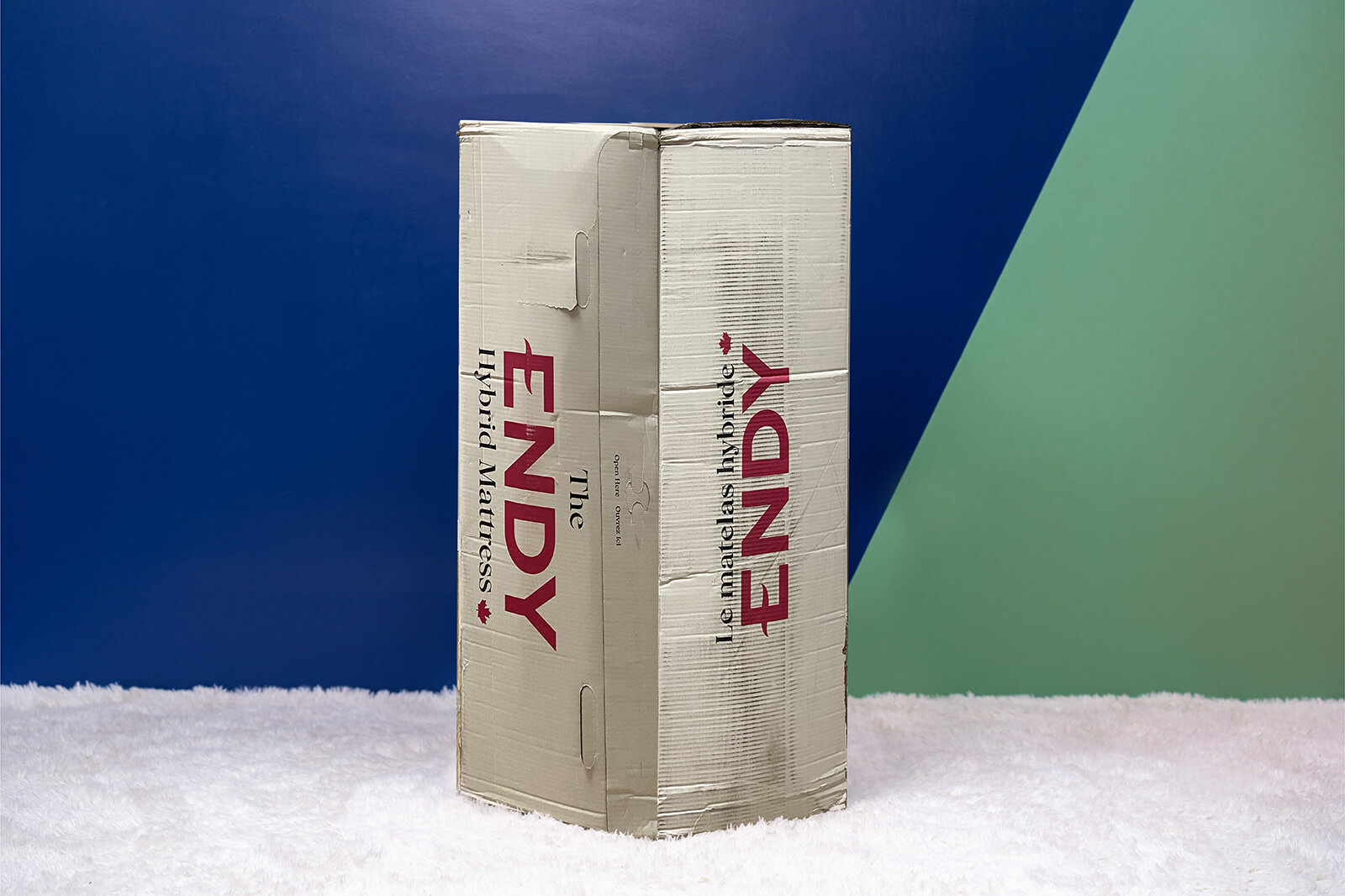 Photo of the Endy Hybrid Mattress box on the floor in a bedroom taken from a front angle.