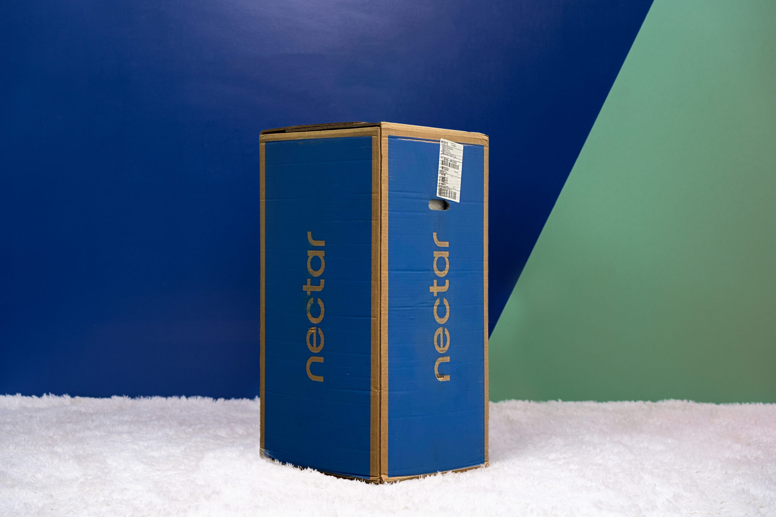 Photo of the Nectar Classic Mattress box on the floor in a bedroom taken from a front angle.