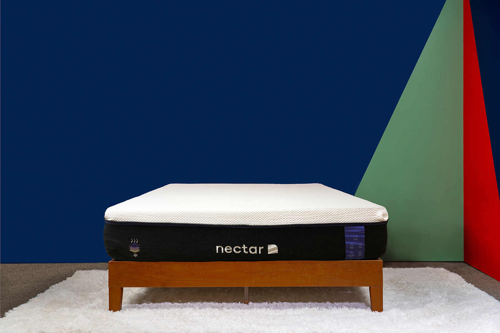 Distant photo of the Nectar Premier Mattress on a bedframe in a bedroom taken from a front angle.